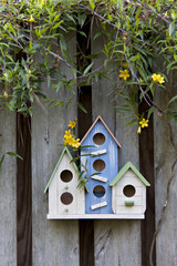 Three cute birdhouses with spring flowers and old rustic wooden fence