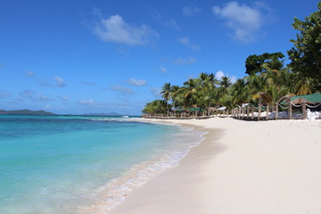 View along a deserted Caribbean beach with white sand and blue sky