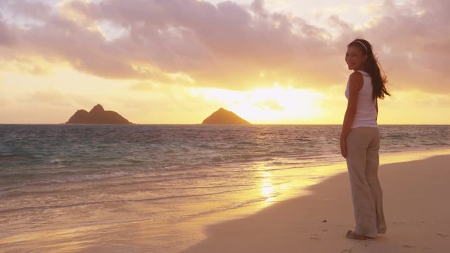 Girl looking at camera at sunrise beach before yoga on Lanikai, Oahu, Hawaii. Mixed race Asian Caucasian women smiling happy enjoying beautiful pristine beach.