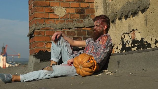 young attractive man with monster zombie make up and pumpkins