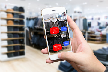 ugmented reality marketing concept. Hand holding smart phone use AR application to check number of social media like and sale price in retail fashion shop