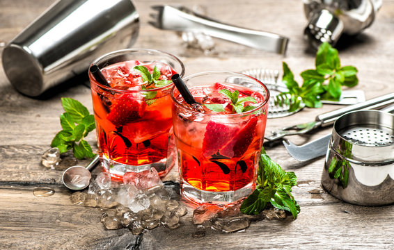 Red drink with strawberry, mint leaves, ice. Cocktail accessorie