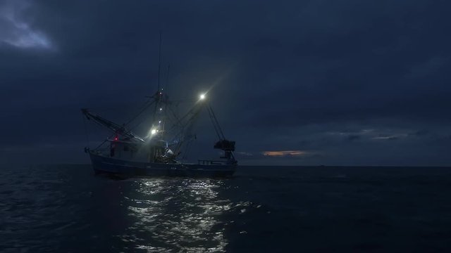Shrimping trawler fishing at the first light of dawn with nets in the water.