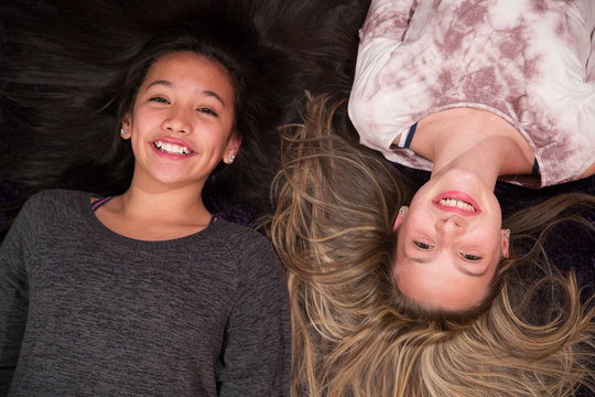 two young girls playing on the floor with hair spread out