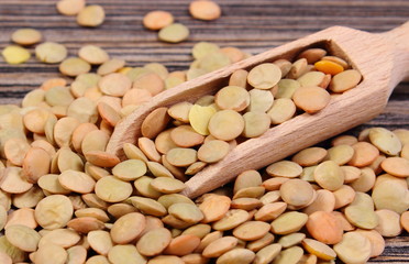 Heap of green lentil with spoon on wooden background