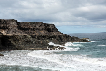 Obraz premium Wave splashing over a rock on the beach of Puertito de los Molinos on Fuerteventura. Canary Island, Spain