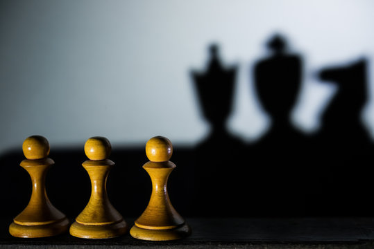 Three Chess Pawn Casting Queen King And Knight Shadow In Dark Concept Of Strength And Aspirations