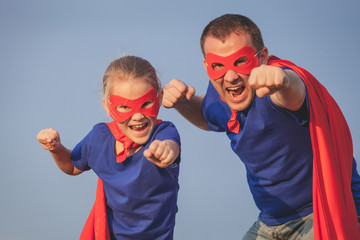 Father and daughter playing superhero outdoors at the day time.