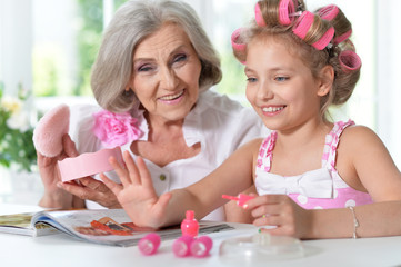 Obraz na płótnie Canvas little girl with granny with magazine and nail polish