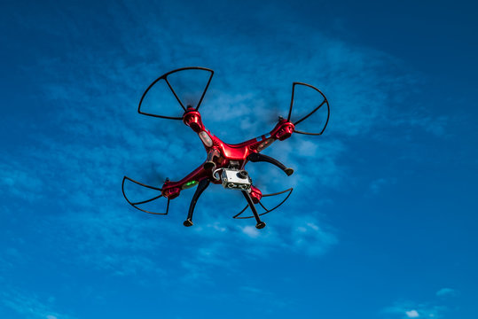 Roter Quadrocopter mit Actioncam ganz nah von unten in der Luft