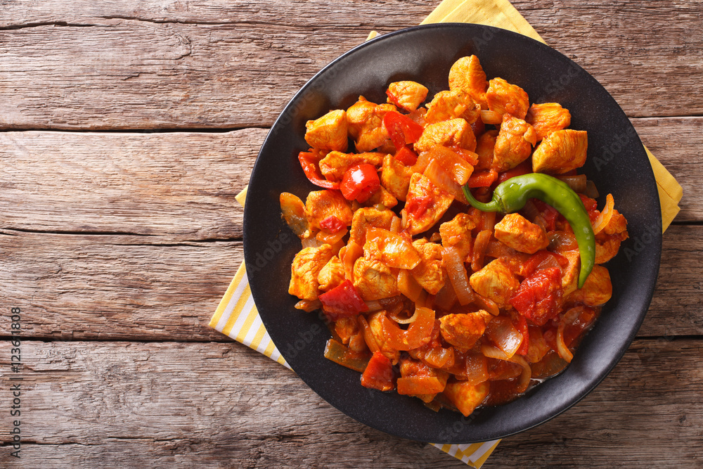 Wall mural spicy chicken jalfrezi with pepper and onion close-up. horizontal top view