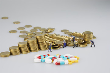 Stack of gold coin with miniature people and medicine