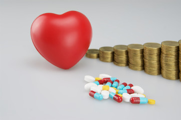 Stack of medicine and red heart with gold coins