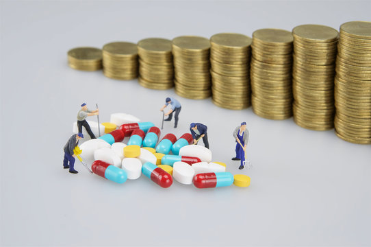 Stack of medicine with miniature people and blur coins