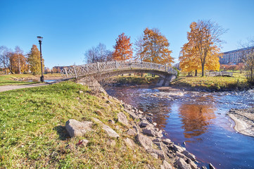 Fototapeta na wymiar across the river bridge in the autumn park