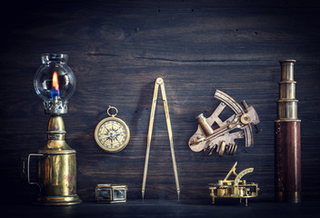 Compass, nautical lamp, sextant, telescope, old coins and a sundial on the captain's Desk.