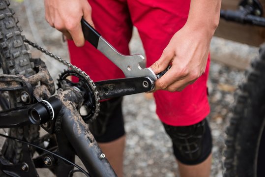 Male cyclist repairing his bicycle in forest