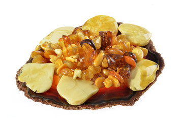 Group of amber beads and tiles,on red agate on a plate, isolated white background