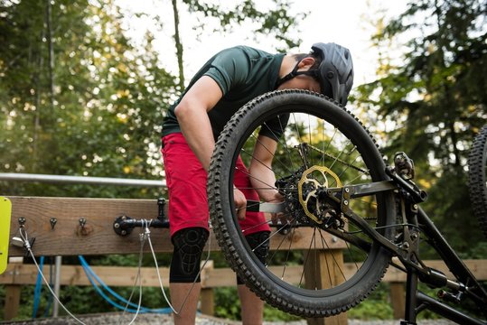 Male cyclist repairing his bicycle in forest