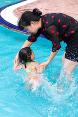 Asian Chinese Mom Teaching Little Girl Swimming At The Pool