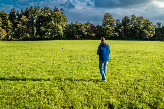 Mann auf Wiese nahe Waldstück steuert seinen Quadrocopter