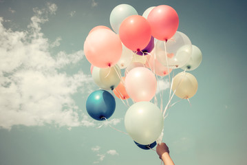 Hands of girl holding multicolored balloons done with a retro vintage filter effect, concept of happy birthday in summer and wedding honeymoon party (Vintage color tone)
