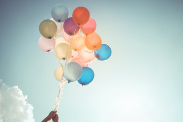 Hands of girl holding multicolored balloons done with a retro vintage filter effect, concept of...