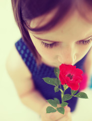 Fototapeta premium Portrait of little beautiful girl is smelling flowers