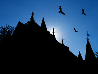 halloween background with silhouettes of castle roofs with  weathervanes and three flying bats