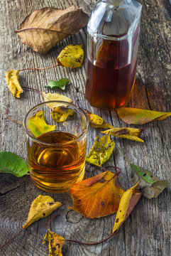 glass of whiskey with autumn leaves on the wooden table
