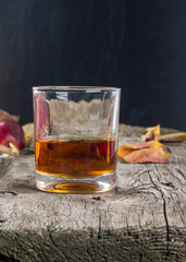 glass of whiskey with autumn leaves on the wooden table