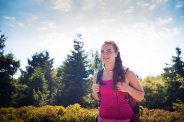 Beautiful young woman/girl/female tourist during hiking the mountain/trekking/backpacking trip on a beautiful sunny summer day