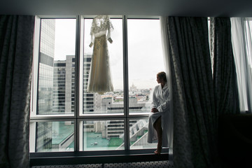 Lady in white bathrobe sits on the windowsill with great industr