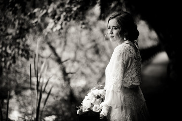 Stunning bride looks thoughtful standing in the garden