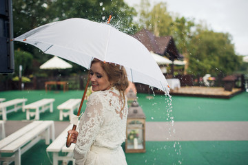 Rain falls over a stunning bride under an umbrella