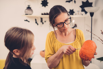 Daughter and mother creating Jack-O-Lantern