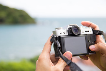 Hand holding a mirrorless digital camera prepare for take a land