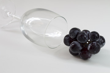 black grape and wine glass on white table