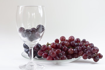  grape in dish glass and grape in wine glass on white table