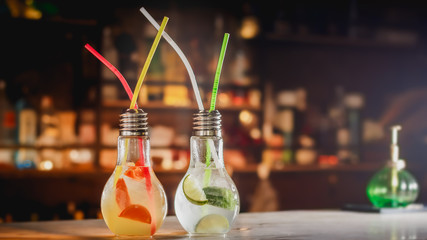Fruity caipirinha cocktail in bottle shaped like a lamp on bar counter.