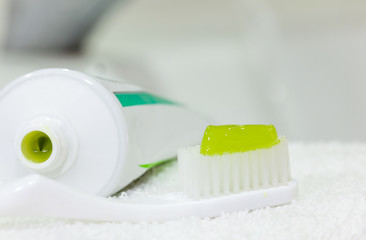 Fototapeta na wymiar Toothbrush with green toothpaste on towel, close up