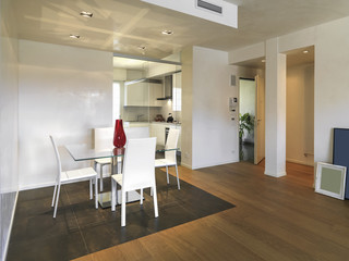interior view of a modern living room in foreground the dining table overlooking on the entrance the floor is made of wood