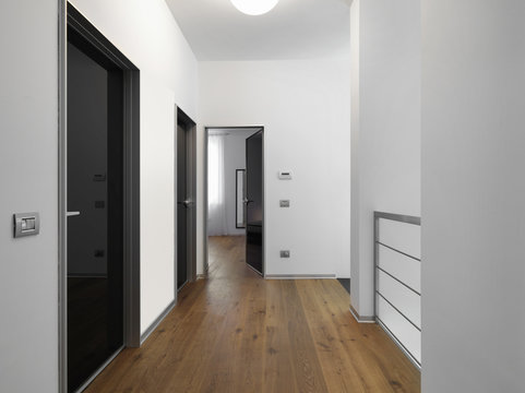 modern corridor with several doors and wooden floor