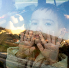 Little boy looking through window