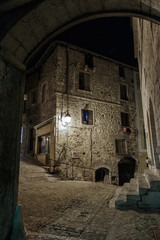 Narrow cobbled street in old town Peille at night, France.