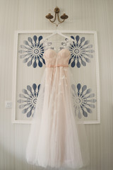 beige and white casual wedding dress hanging near the wall
