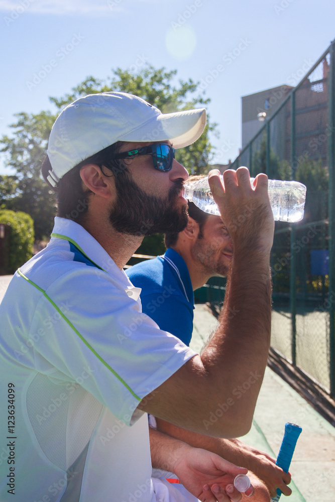 Wall mural two professional players hydrating after a hard game of tennis. they are friends and are sitting res