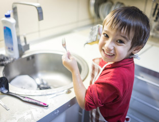 Fototapeta na wymiar A little cute boy washing dishes