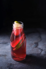 Glass bottle with citrus cocktail on the dark background vertical