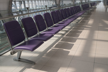 Airport terminal interior with rows of empty seats, city view an